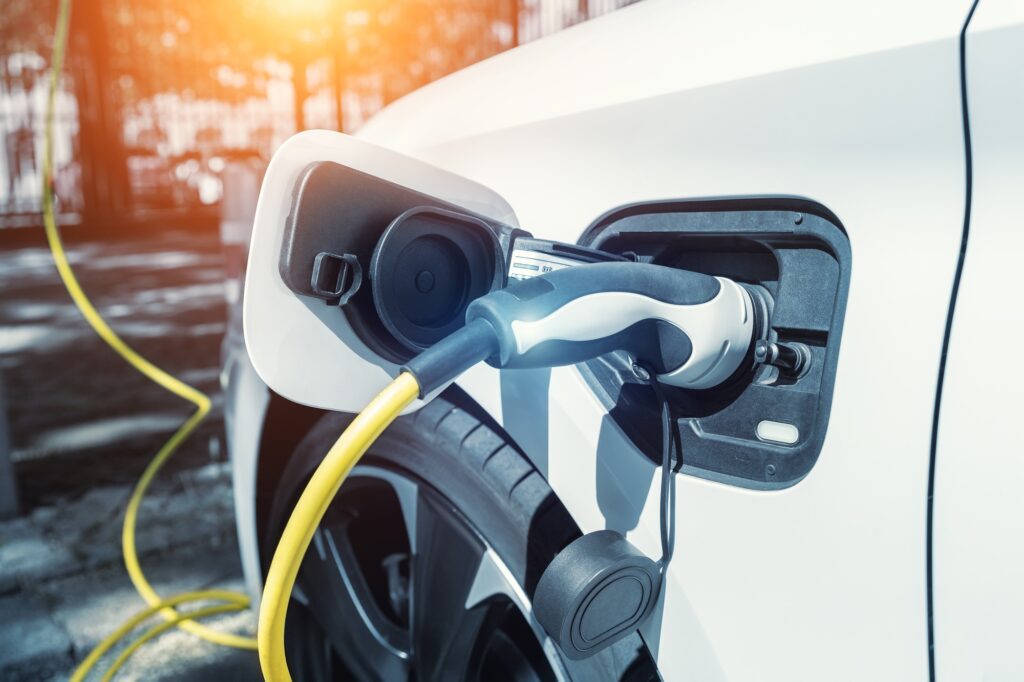 Close-up modern electric plug-in hybrid car parked near fast charger charging station