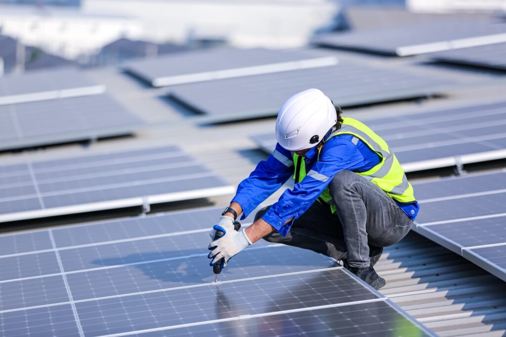 Solar panel installer installing solar panels on roof of warehouse