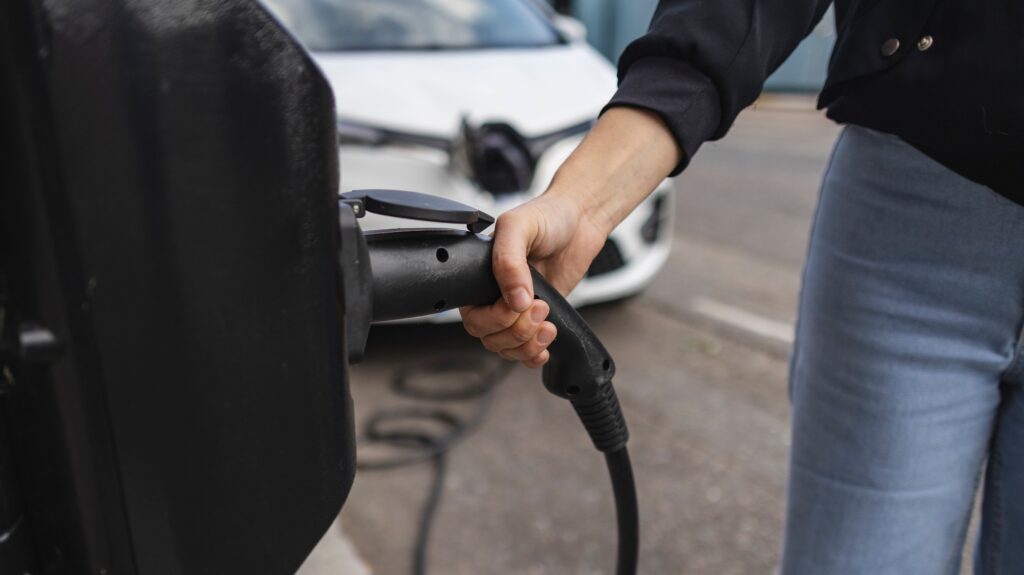 Woman holding power cable plugging into electric car charger in london